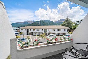 A balcony with a view of a building and mountains. - Amity Serviced Apartments (Queenstown)