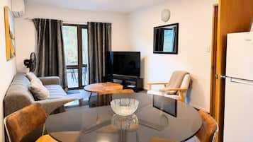 Un salón moderno con una mesa de vidrio, sofá, sillas, un televisor y una puerta con la etiqueta 'Haier'.