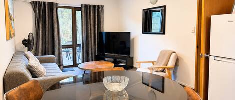 Un salón moderno con una mesa de vidrio, sofá, sillas, un televisor y una puerta con la etiqueta 'Haier'.