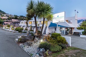 A modern building with a sign for 'amityqueenstown apartments' and a parking lot.