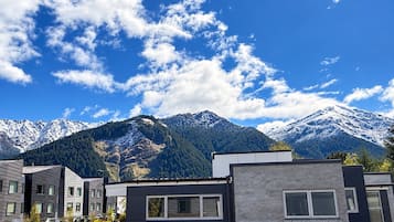 A modern building with a flat roof and large windows, set against a backdrop of snow-capped mountains and a clear blue sky.