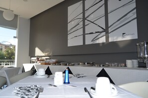 A dining area with tables set for a meal, a large abstract painting on the wall, and a view of the outdoors. - Madeira Bright Star Hotel (Funchal)