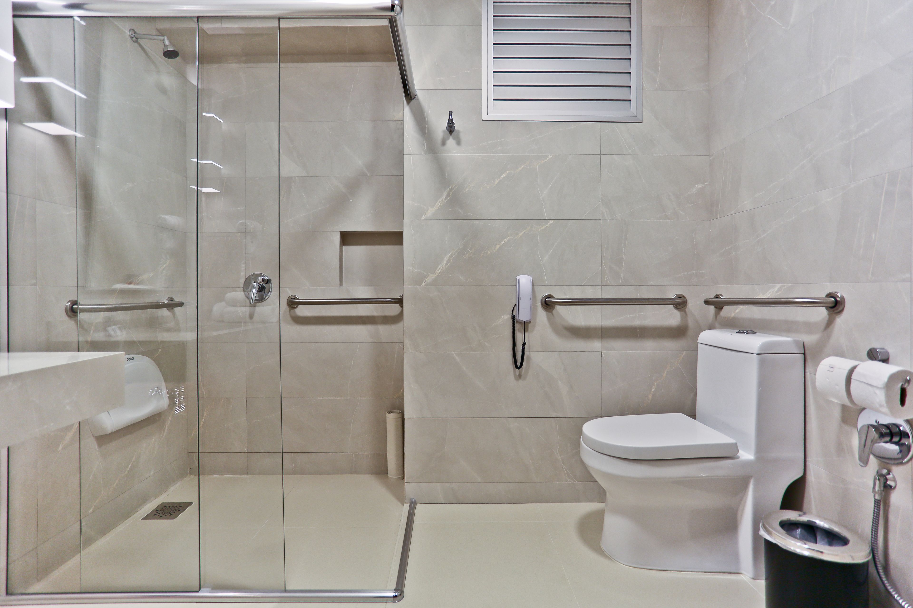 A modern bathroom with a glass-enclosed shower, a toilet, and a bidet.