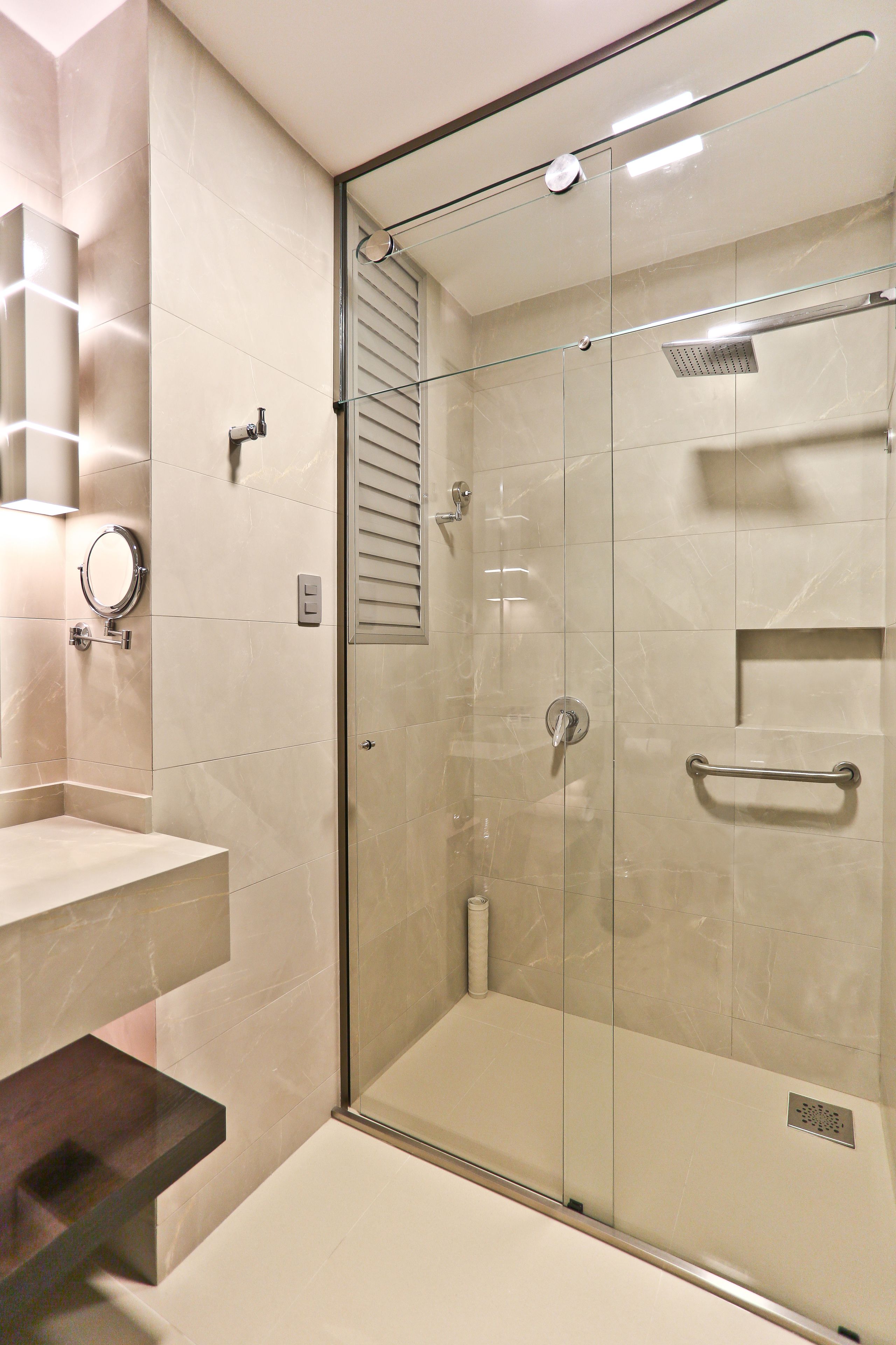 A modern bathroom with a glass-enclosed shower, a vanity with a mirror, and a towel rack.