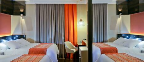 A hotel room with two beds, a desk, and a chair.