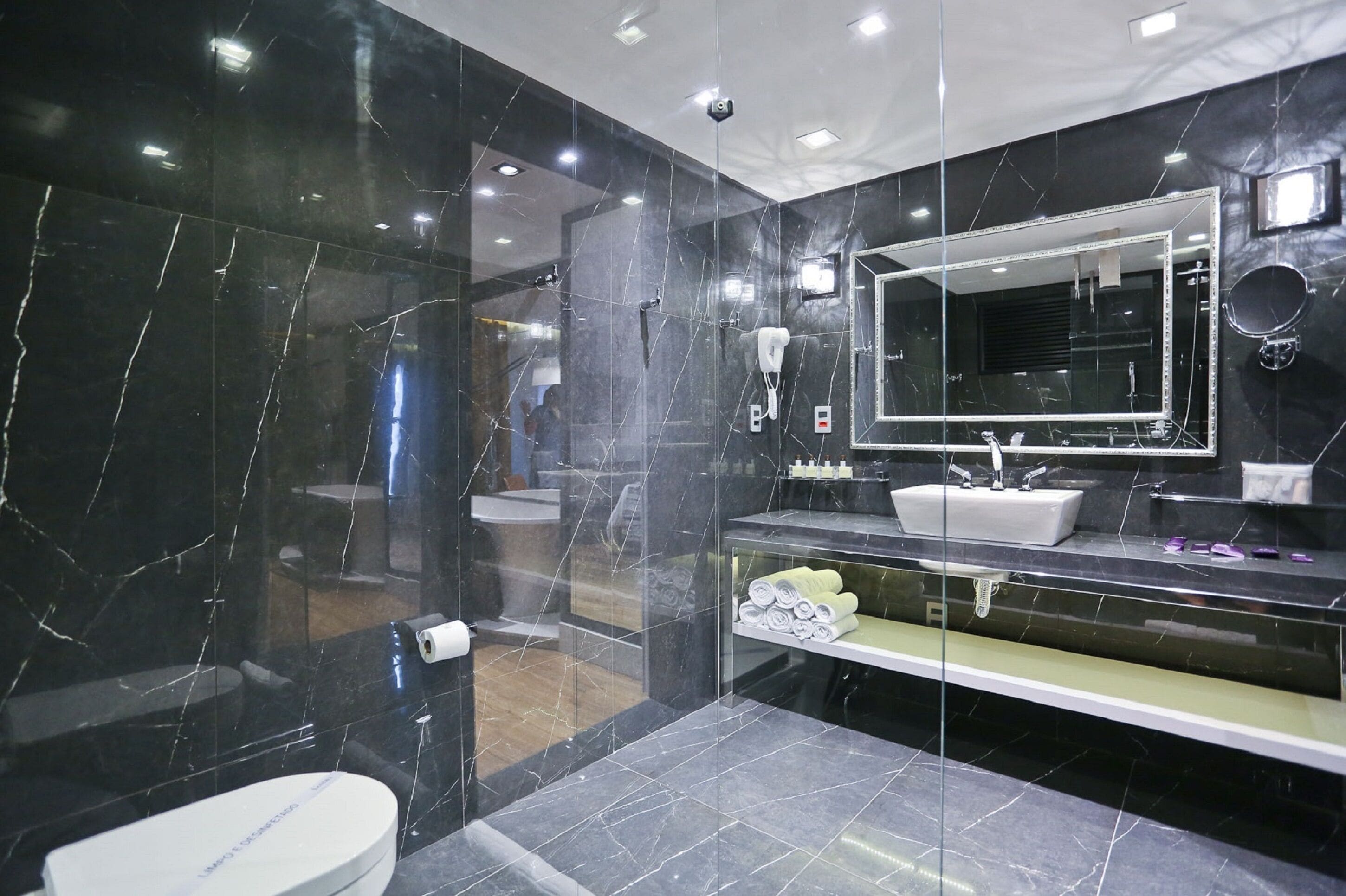A modern bathroom with a large mirror, a white sink, and a glass-enclosed shower area.
