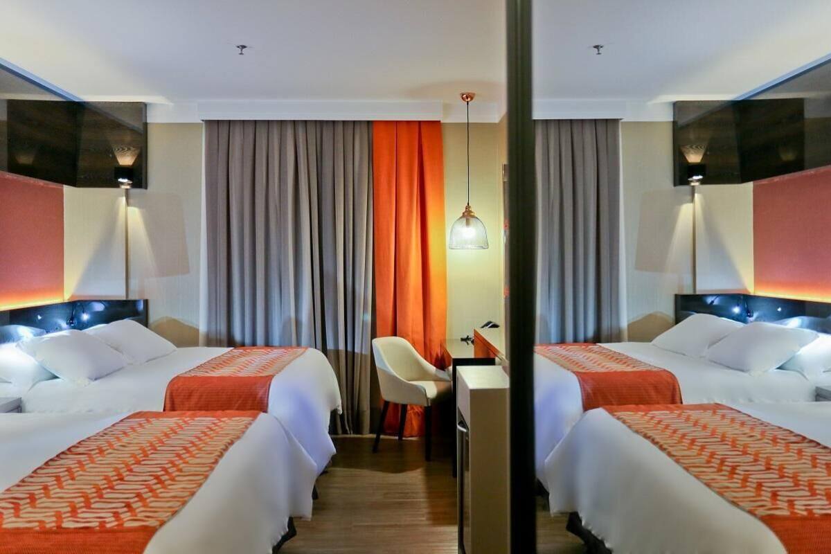 A hotel room with two beds, a desk, and a chair.