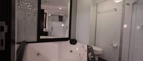 A modern bathroom with a large bathtub, a toilet, and a shower area.