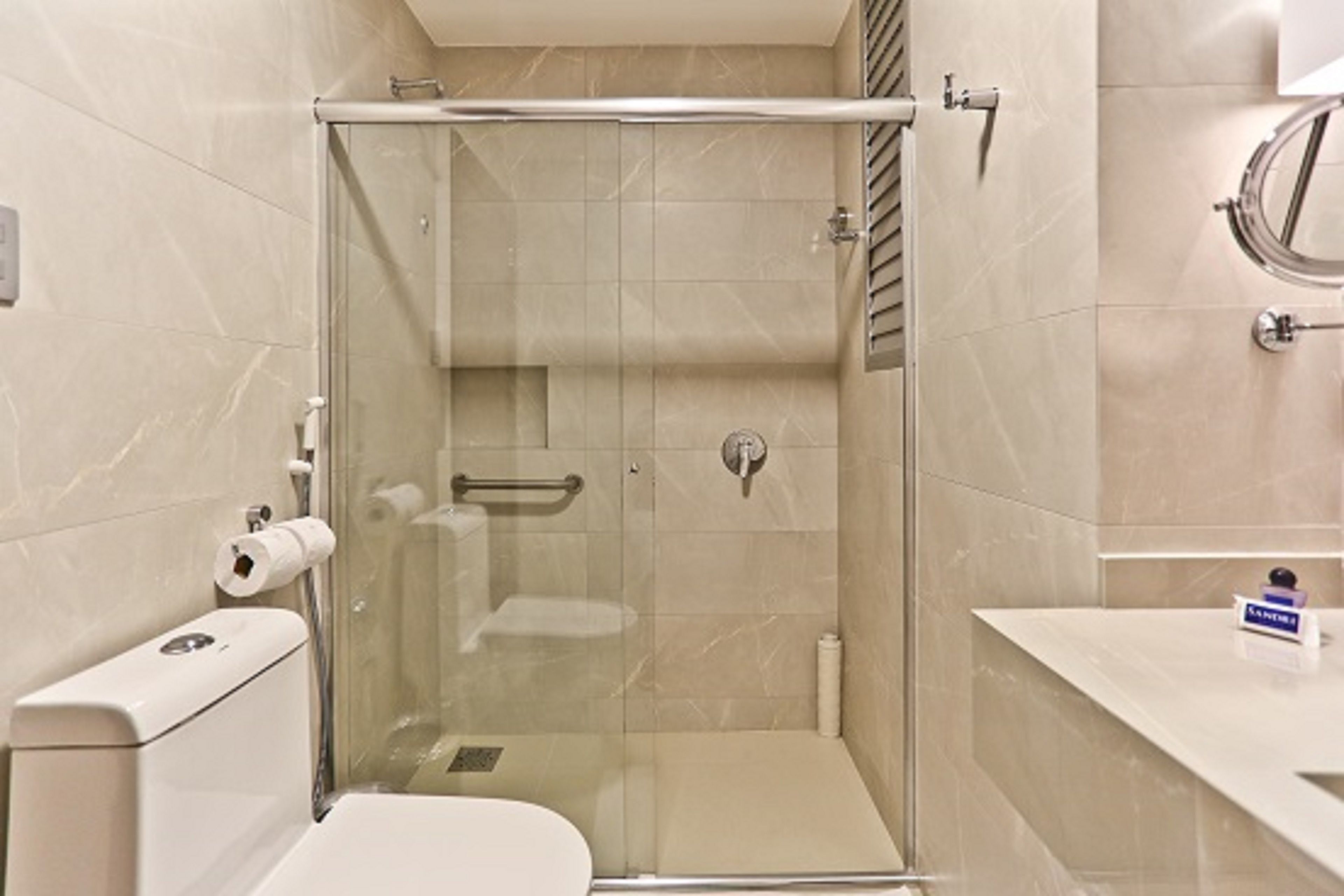 Un baño moderno con ducha envuelta en vidrio, inodoro y lavamanos.
