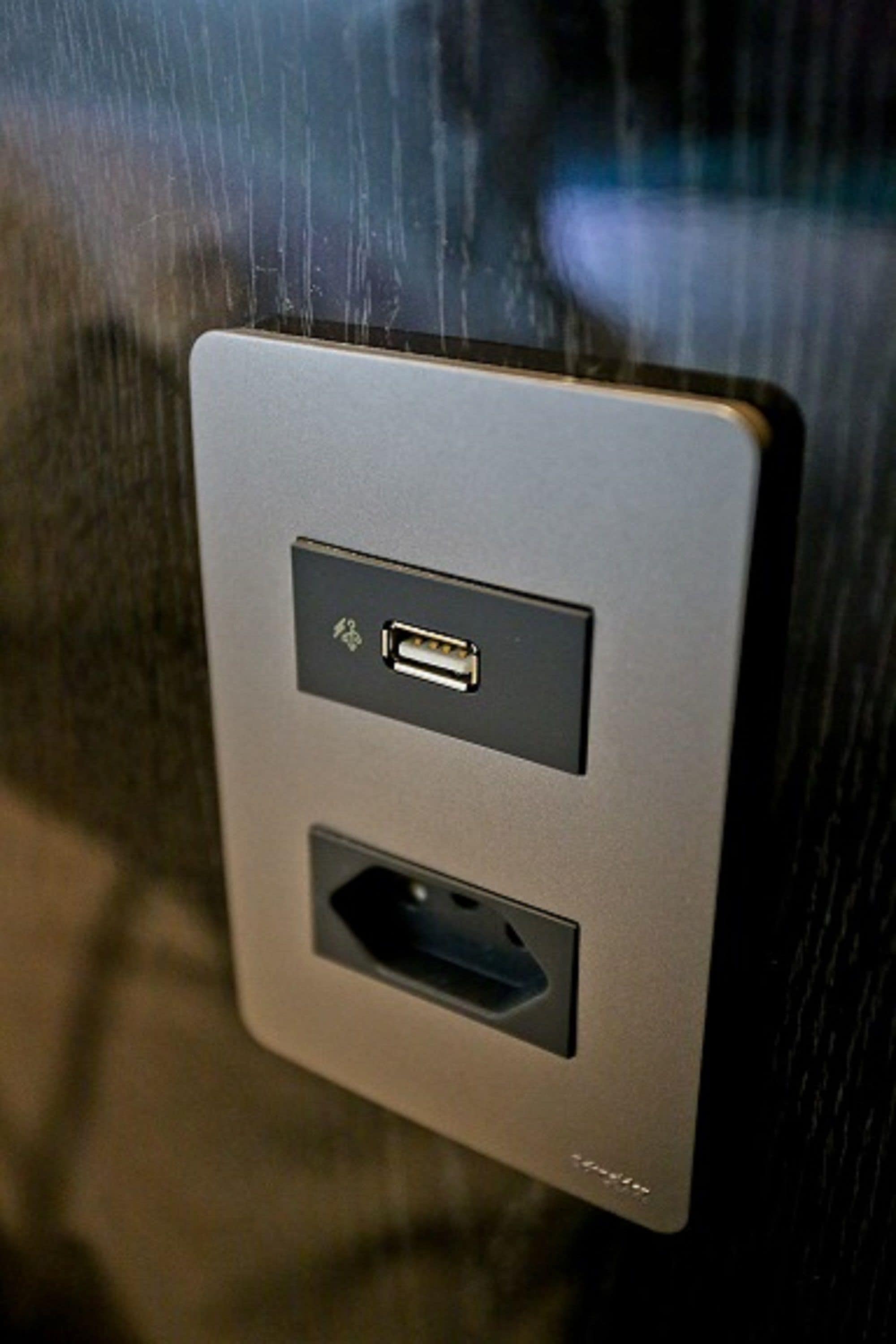 A wall-mounted electrical outlet with a USB port and a power socket.