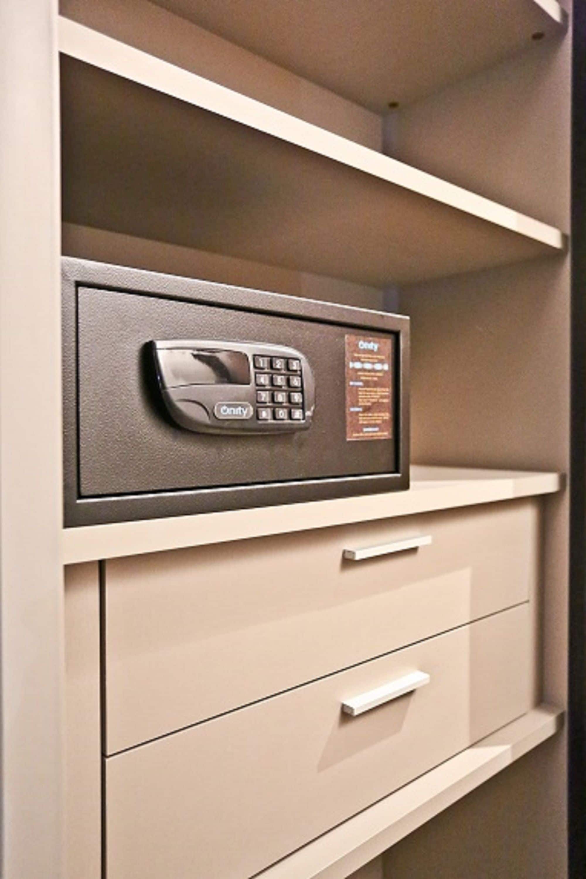 A safe with a keypad and a card reader, mounted on a beige cabinet with drawers.