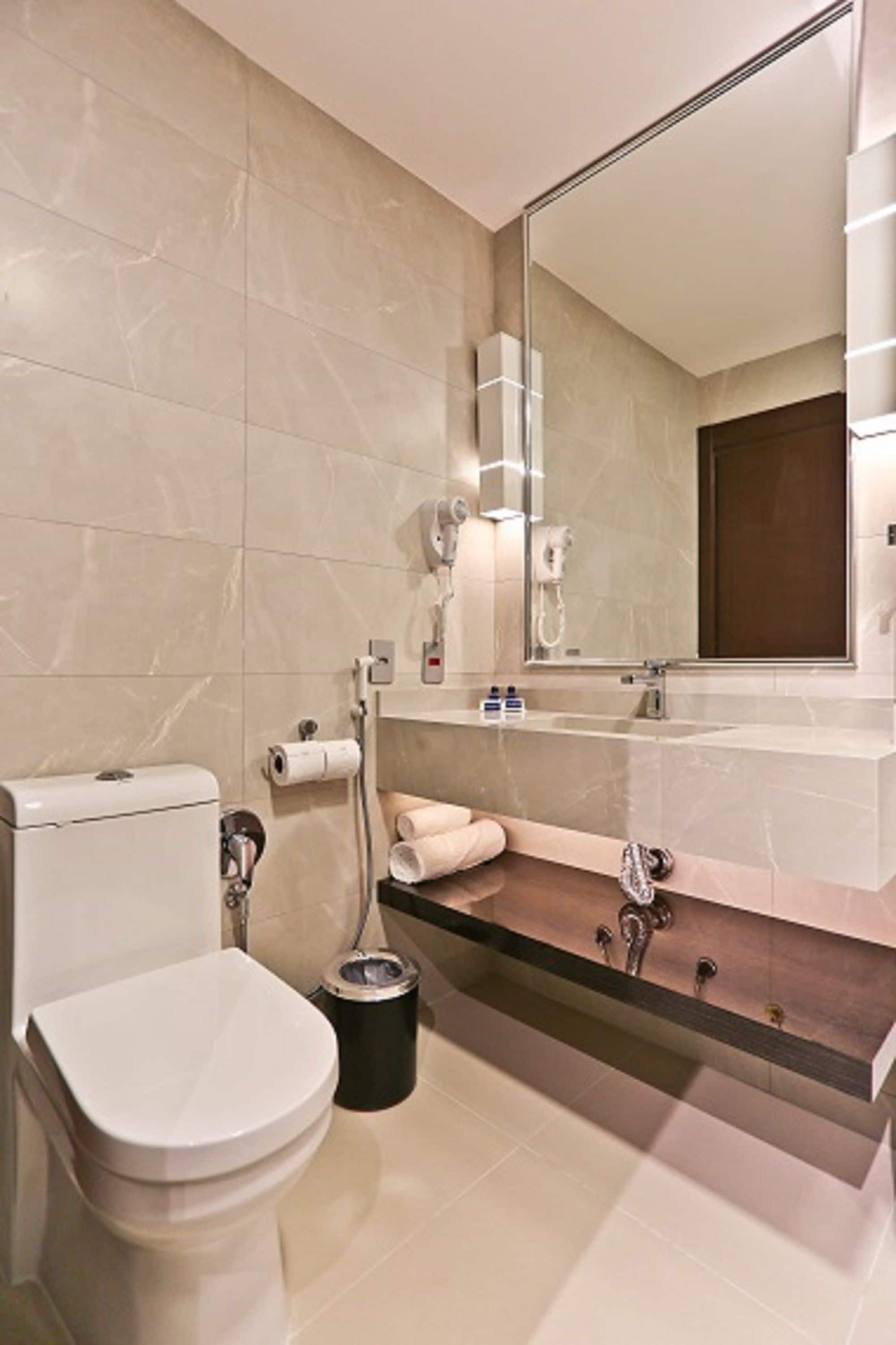 Une salle de bain moderne équipée de toilettes, d’un lavabo et d’un miroir.