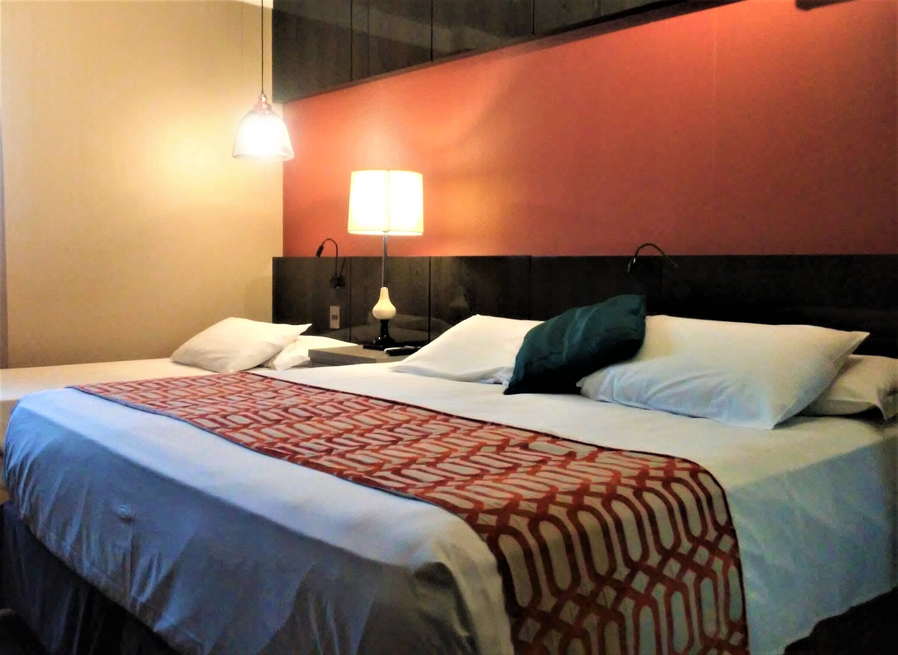 Una habitaci ón de hotel con una cama, dos lámparas de noche y una colcha estampada.