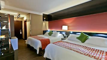 A hotel room with two beds, a desk, and a mirror.