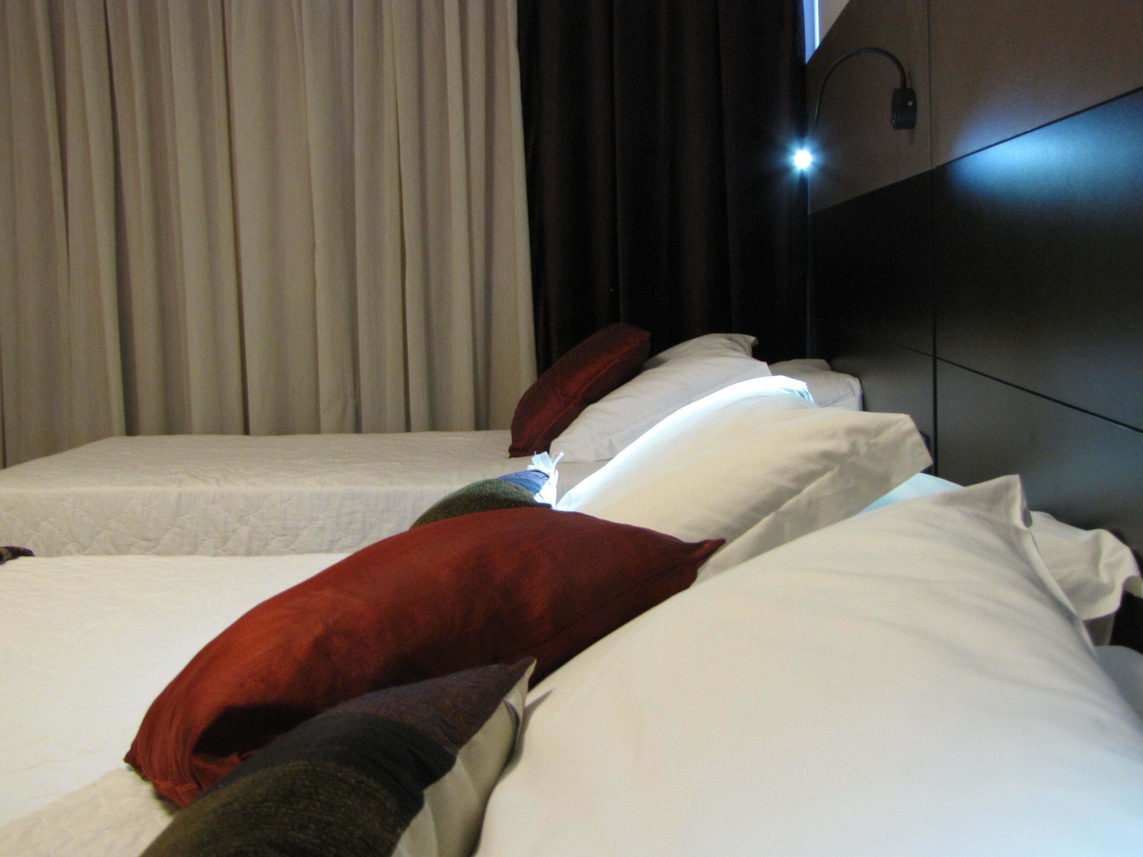 A hotel room with two beds, each with white linens and multiple pillows.