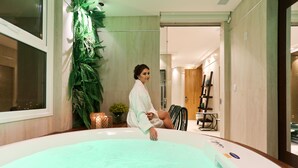 A person sitting in a large, modern bathtub with a control panel. - Sandri Palace Hotel (Itajai)