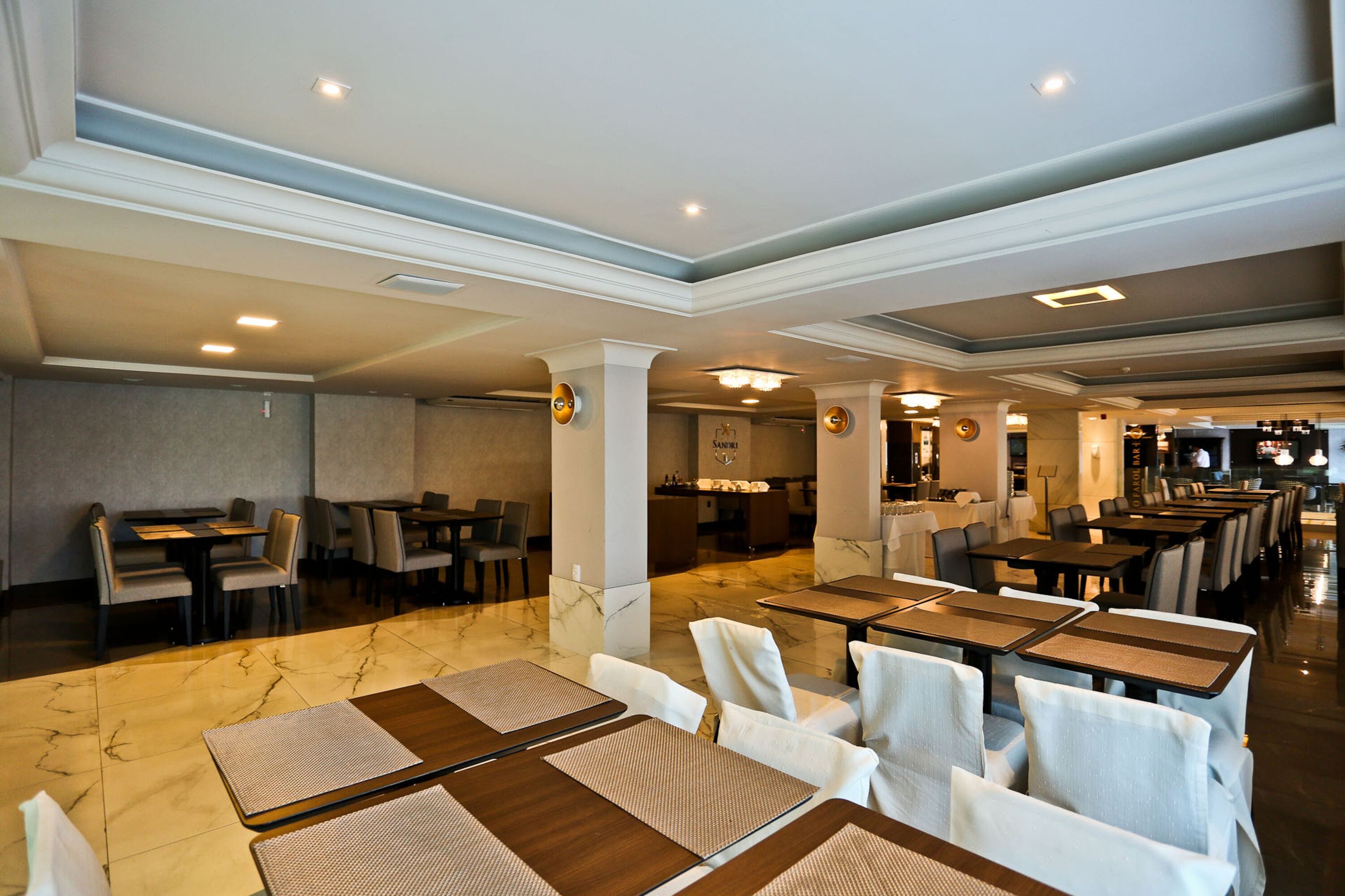 Un hall d’hôtel spacieux, doté de plusieurs espaces de restauration, d’un sol en marbre et d’un éclairage moderne.