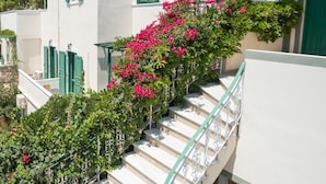 Un edificio blanco con contraventanas verdes y una escalera con barandilla de metal.