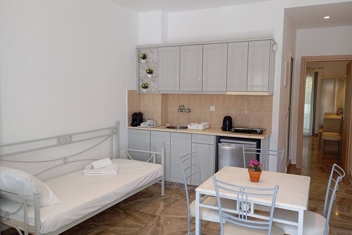 A compact room with a bed, a small dining table, a kitchenette, and a bathroom.