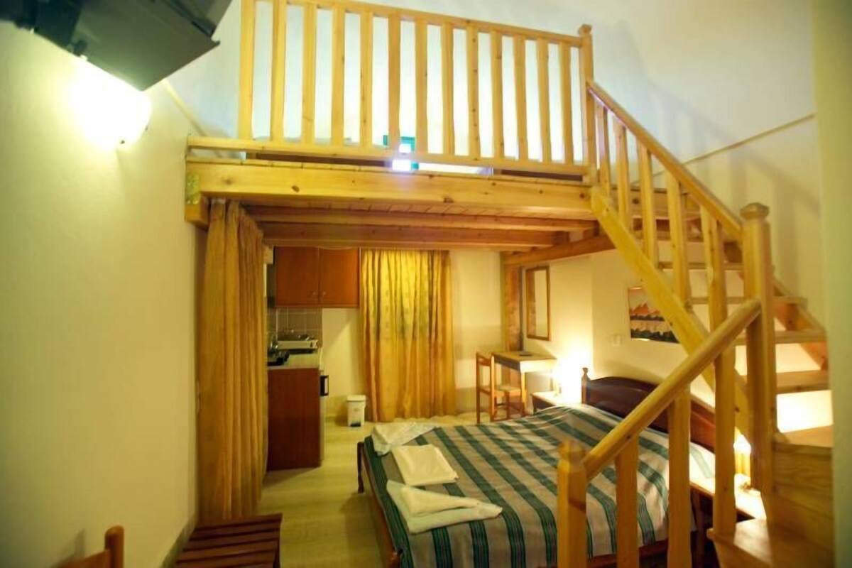 A compact room with a bed, a desk, and a small kitchenette.