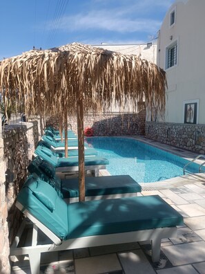 Una piscina al aire libre de temporada, sombrillas
