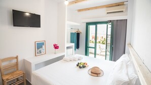 Un dormitorio con cama, una silla, un televisor, un ventanal y un balcón con vistas.