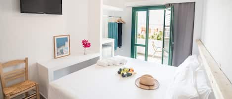 A bedroom with a bed, a chair, a TV, a window, and a balcony with a view.