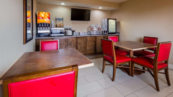A compact kitchen with a coffee machine, a TV, and a refrigerator.