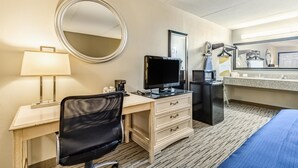 Una habitación de hotel con escritorio, silla, televisión, minibar y cama.