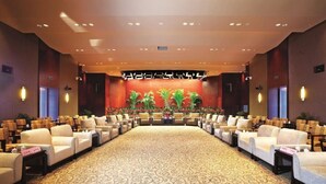 A conference room with a patterned carpet, rows of chairs, and a stage with plants. - Quanzhou Guest House Hotel (Quanzhou)