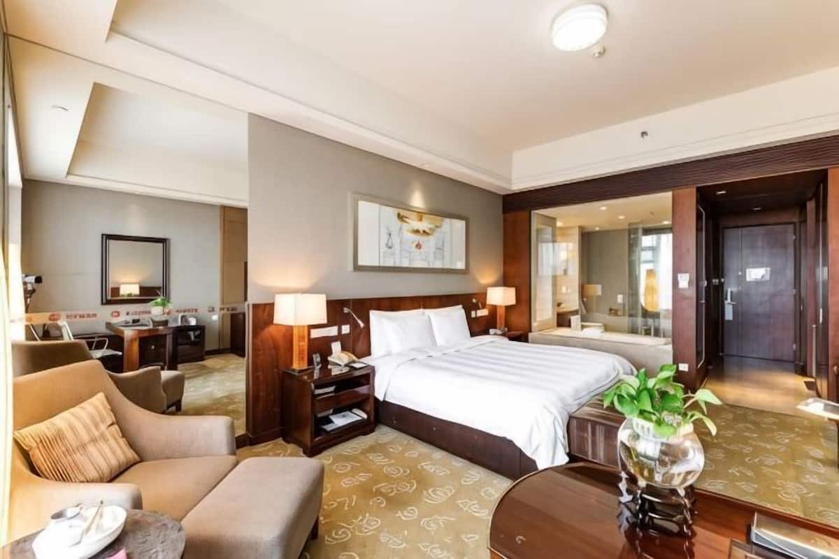 Een hotelkamer met een bed, een bank, een bureau en een spiegel.