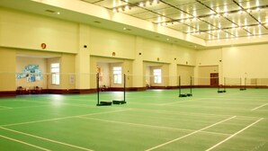 A large indoor space with a green floor, marked lines, and multiple volleyball nets. - Quanzhou Guest House Hotel (Quanzhou)