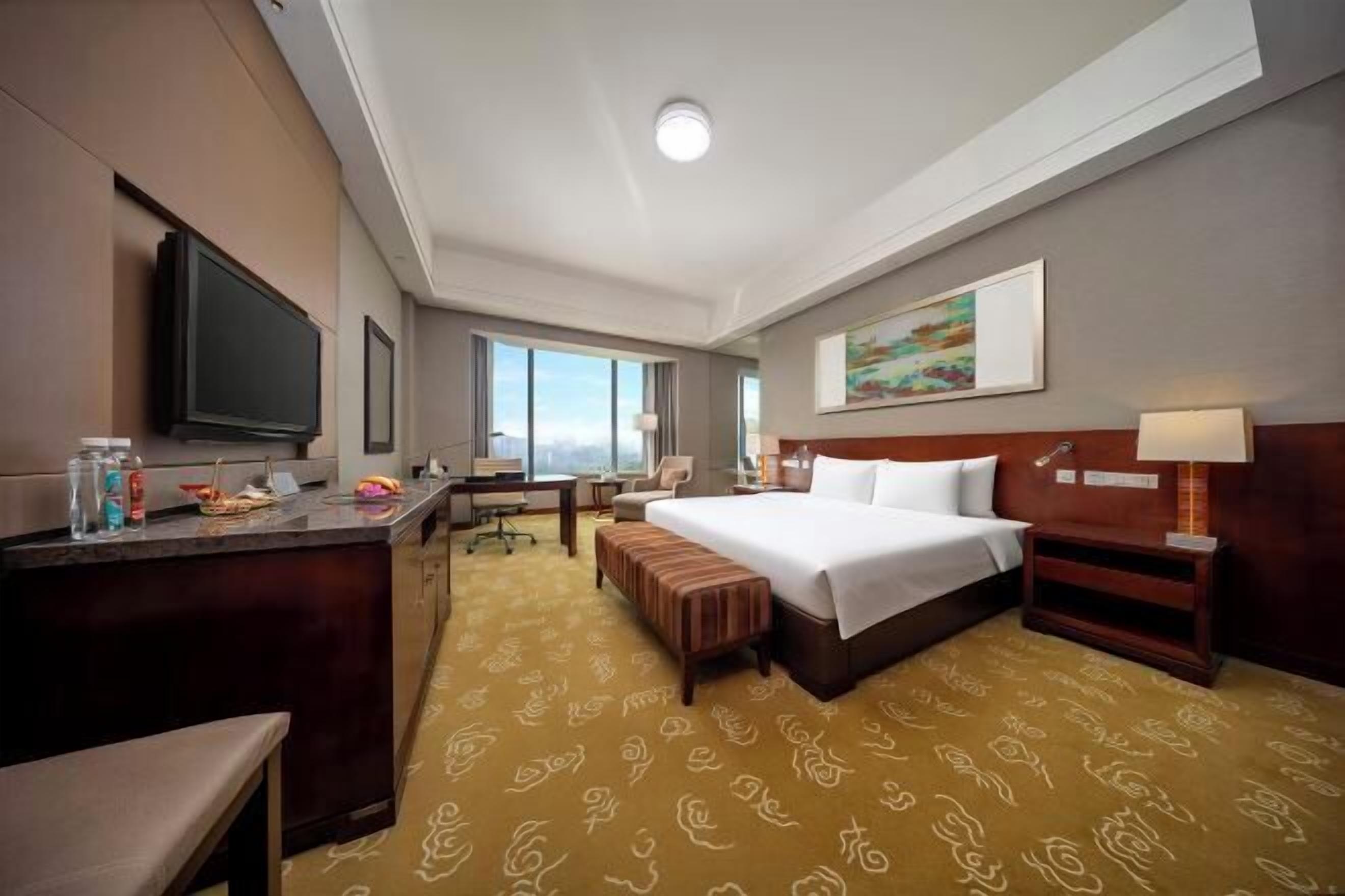 Une chambre d’hôtel comprenant un lit, une table de chevet, un bureau, une chaise et un téléviseur.