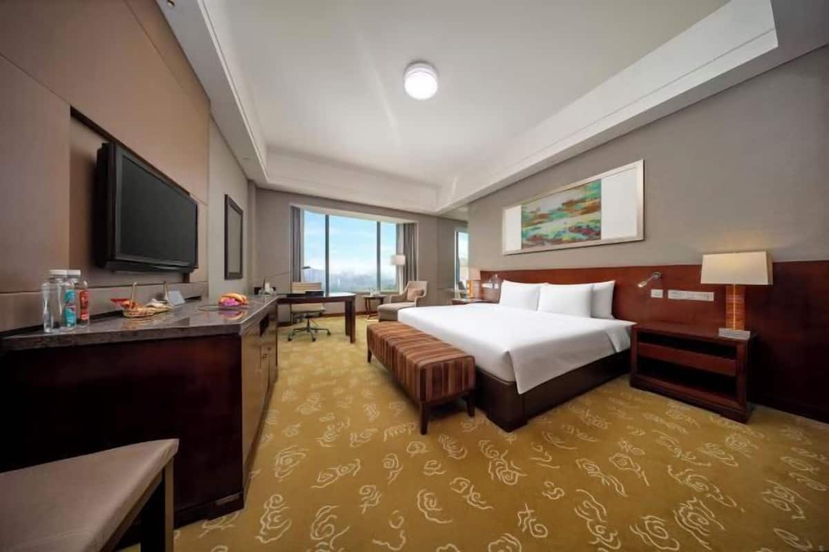 Een hotelkamer met een bed, nachtkastje, bureau, stoel en een televisie.
