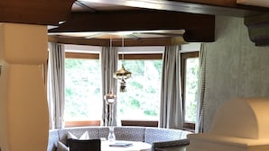 A cozy room with a bed, a sofa, a dining table, and a window with curtains. - Brugger´s Genießerhotel Lanersbacherhof (Tux)