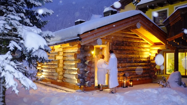 A log cabin with a warm interior light, surrounded by snow. - Brugger´s Genießerhotel Lanersbacherhof (Tux)