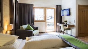 A hotel room with a bed, a desk, a television, and a view of the outside. - Brugger´s Genießerhotel Lanersbacherhof (Tux)