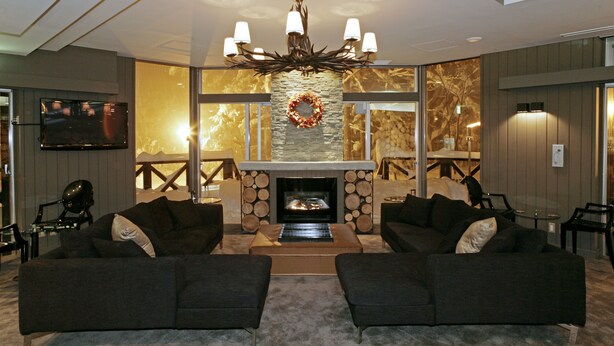 A modern living room with a fireplace, two sofas, a television, and a chandelier. - The Ridge Hotel & Apartments (Hakuba)