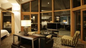 A spacious living area with a large TV, comfortable seating, and a view through large windows. - The Ridge Hotel & Apartments (Hakuba)