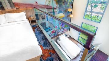A modern hotel room with a large bed, a glass-enclosed balcony, and a view of the outdoors.