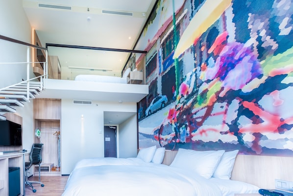 A modern hotel room with a large bed, a desk with a chair, a TV, and a colorful abstract wall mural. - Eastin Hotel Penang (George Town)