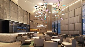 A modern lobby with a bar area, seating arrangements, and a unique ceiling light fixture. - Eastin Hotel Penang (George Town)