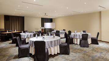 A conference room with round tables, chairs, and a large white lamp.