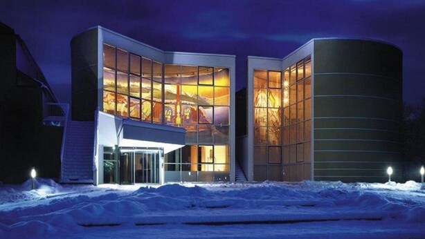 A modern building with a glass facade and a curved structure. - St. Virgil (SALZBURG)