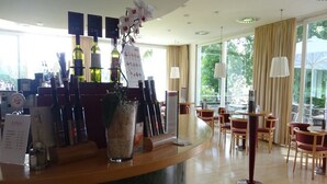 A hotel reception area with a bar, seating, and large windows. - St. Virgil (SALZBURG)