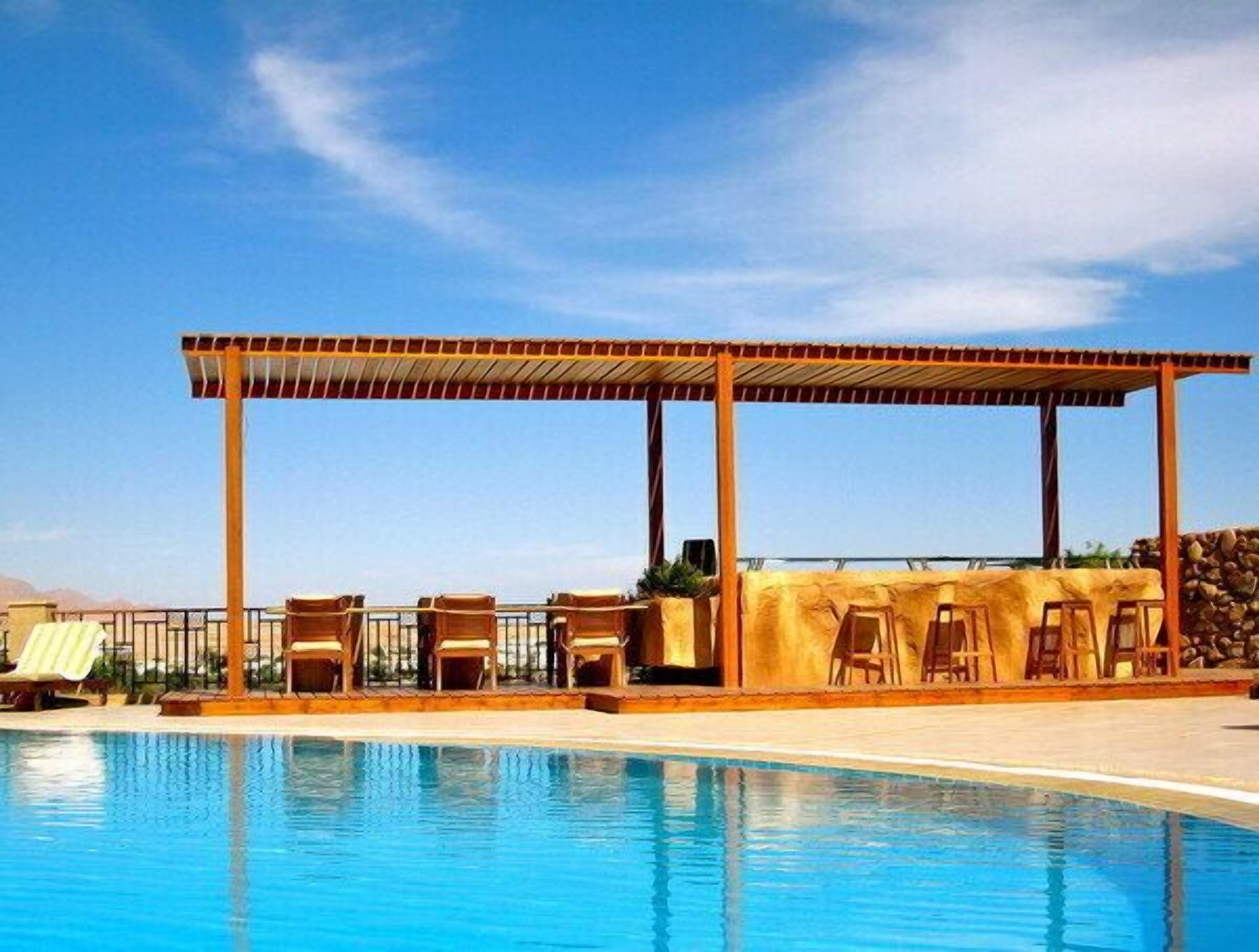 A poolside area with a covered seating area and lounge chairs.