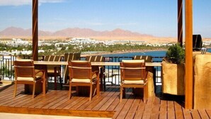 A wooden deck with outdoor seating and a view of a desert landscape. - Eden Rock Hotel (Sharm El Sheikh)