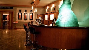 A bar area with a unique green sculpture, framed artwork on the walls, and a wooden counter. - Eden Rock Hotel (Sharm El Sheikh)