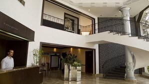 A hotel lobby with a reception desk, a staircase, and a large window. - Eden Rock Hotel (Sharm El Sheikh)