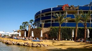 A beachside hotel with a pool area, palm trees, and a clear blue sky. - Eden Rock Hotel (Sharm El Sheikh)
